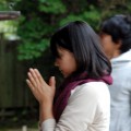 祈りを捧げる若い女性の姿も