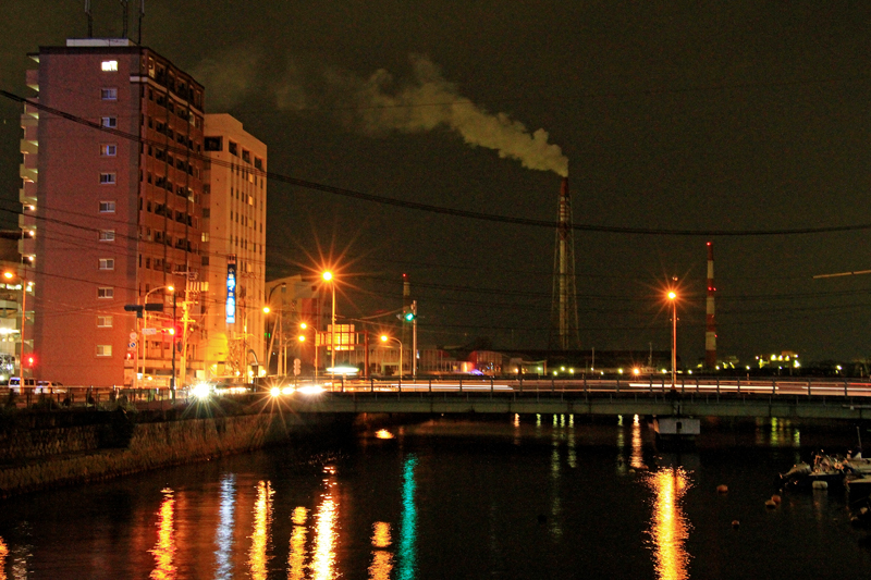 夜の関門港に聳える発電所の煙突。小倉は八幡製鉄所をはじめとする工業の街でもある。